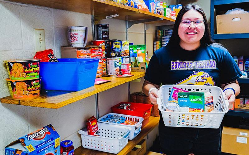 Student holds a basket full of foods available at the Student Food Pantry.